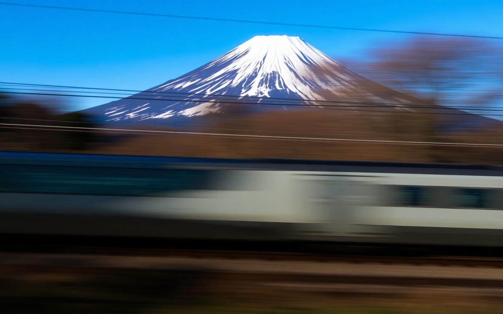 Shinkansen bullet train streaking past Mount Fuji